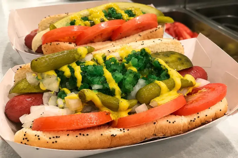 A close-up, authentic shot of a Chicago-style hot dog served in a white paper boat, featuring a poppy seed bun loaded with yellow mustard, neon green sweet relish, sport peppers, chopped onions, sliced tomatoes, and a dill pickle spear.