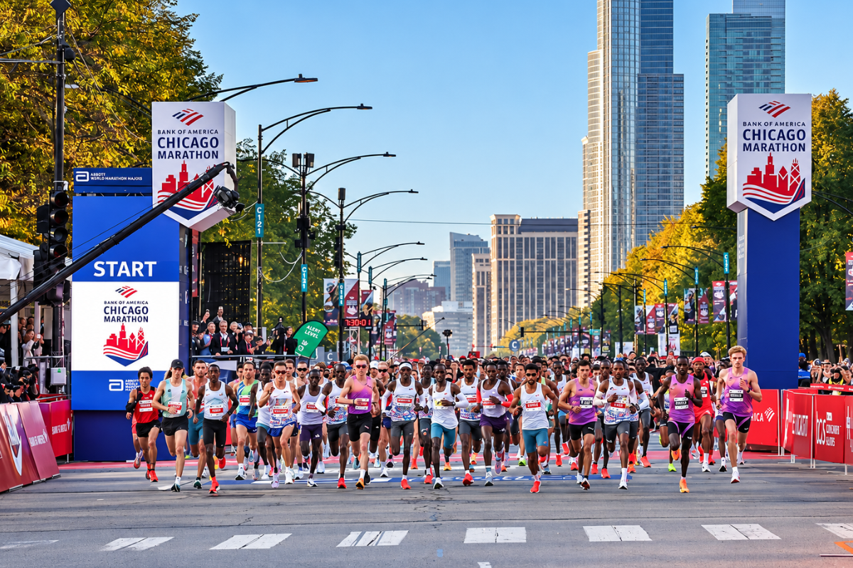 A massive group of elite runners crossing the start line of the Bank of America Chicago Marathon on Columbus Drive, with the downtown Chicago skyline towering in the background.