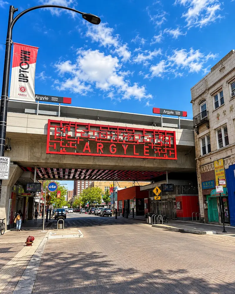 An outdoor view highlights the Argyle CTA train station overpass featuring a large, decorative red metal sign structured with geometric patterns and the word "ARGYLE". The brick-paved shared street below is flanked by historic storefronts, including Hiep Loi Gifts Co., under a bright blue sky.