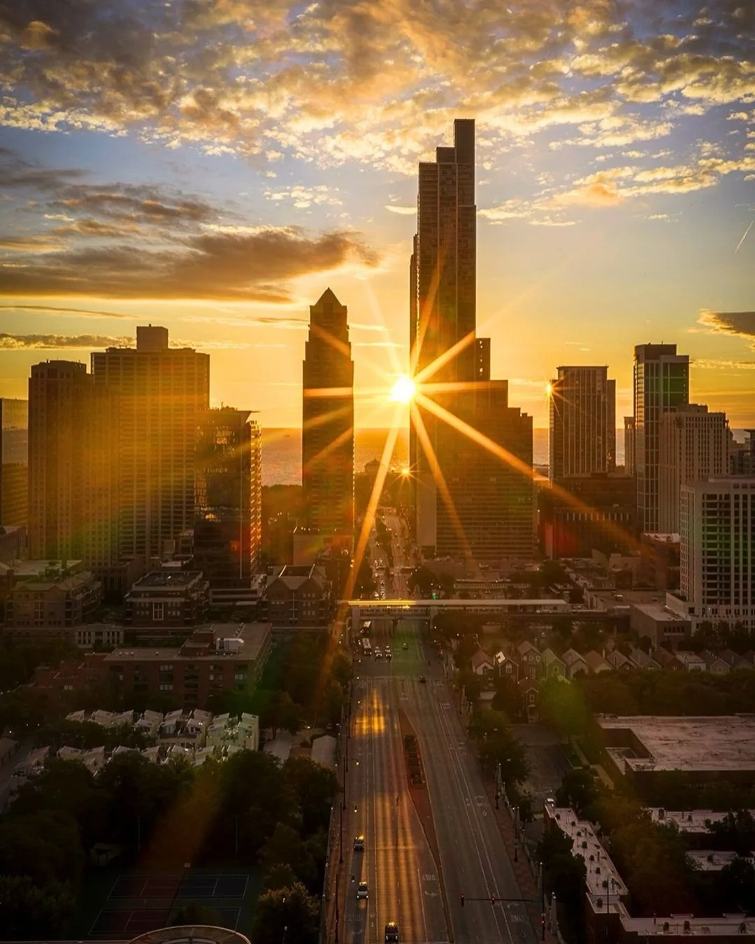 A spectacular view of the Chicagohenge phenomenon, with the setting sun aligning perfectly between downtown Chicago skyscrapers and casting a golden sunburst down the street grid.