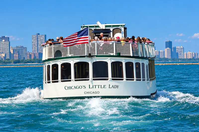 The stern view of the Chicago's Little Lady architecture tour boat navigating the water, featuring a packed, open-air upper passenger deck.