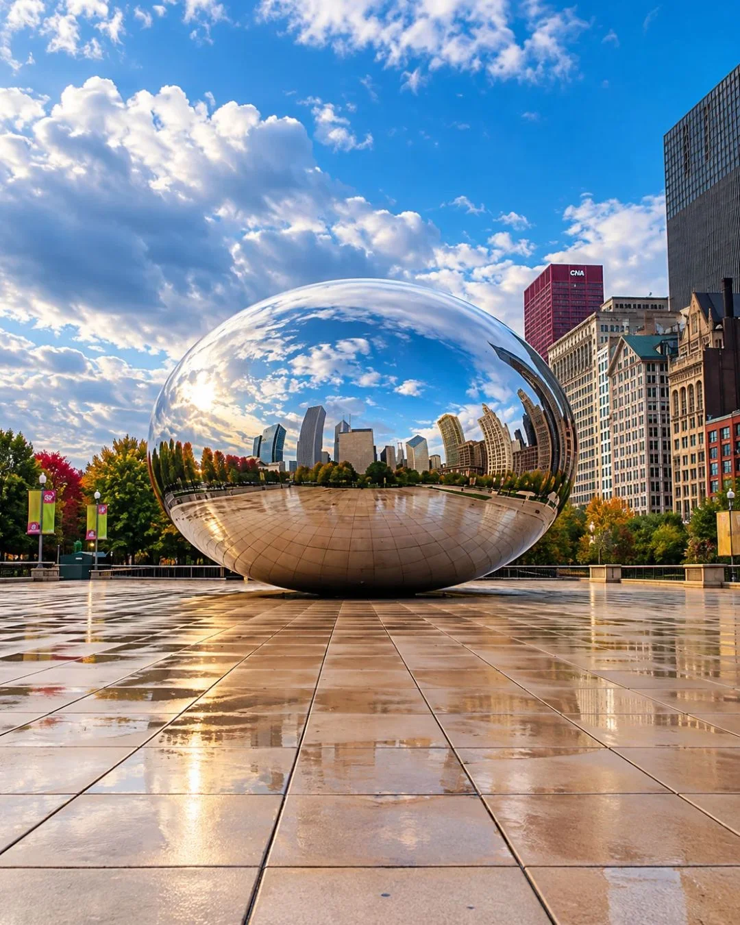 The polished, metallic surface of Cloud Gate in Millennium Park reflects the Chicago skyscraper skyline beneath a dramatic, overcast gray sky. The giant, bean-shaped sculpture rests on a vast, grid-patterned stone plaza that appears damp and entirely devoid of people. Lush green and early autumn trees line the left side of the plaza, contrasting with the dense wall of historic brick and modern concrete high-rises on the right.