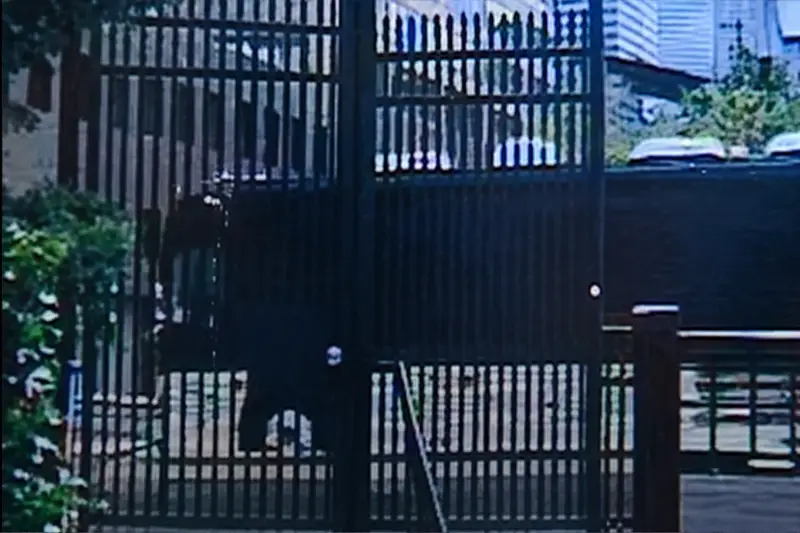 Grainy 2004 security camera footage from the East Bank Club showing the black Dave Matthews Band luxury tour bus driving past a metal fence near the Kinzie Street Bridge.