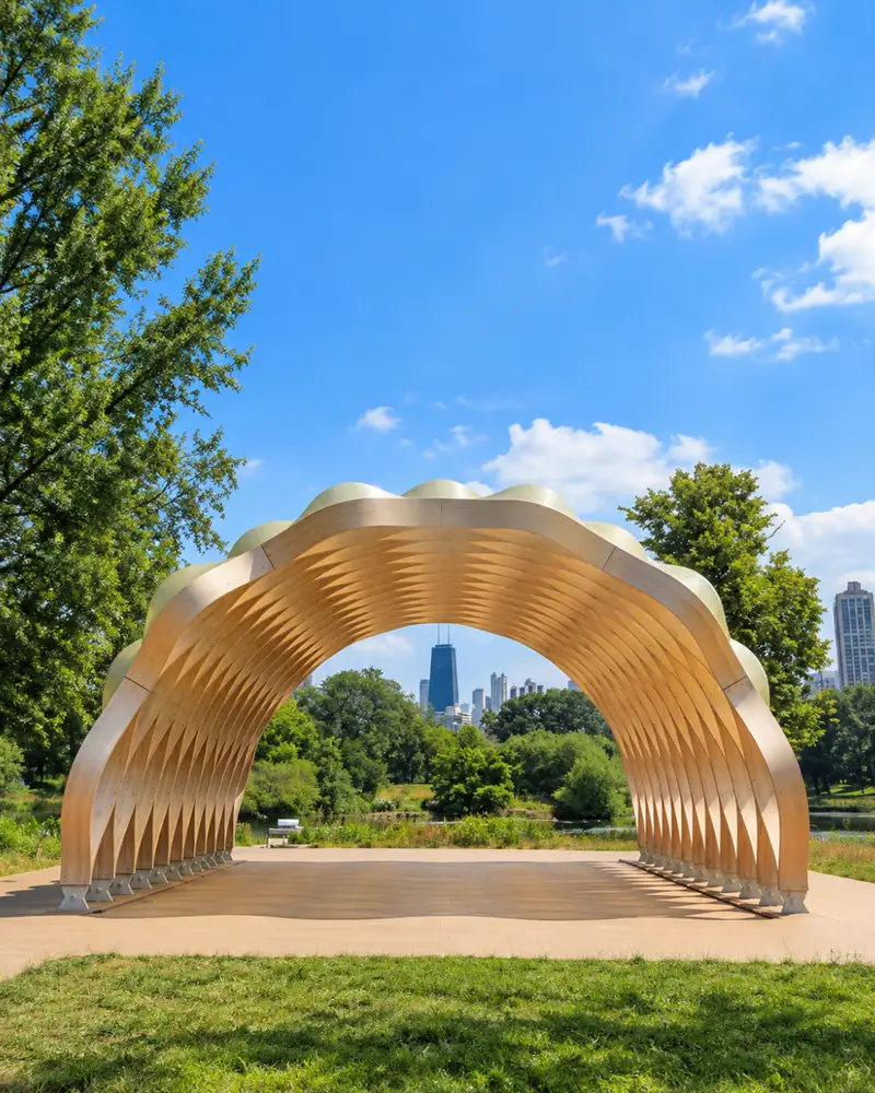 A beautifully designed wooden pavilion known as the Honeycomb at the Lincoln Park Nature Boardwalk, framing a view of the Chicago skyline and John Hancock Center in the distance on a sunny day.