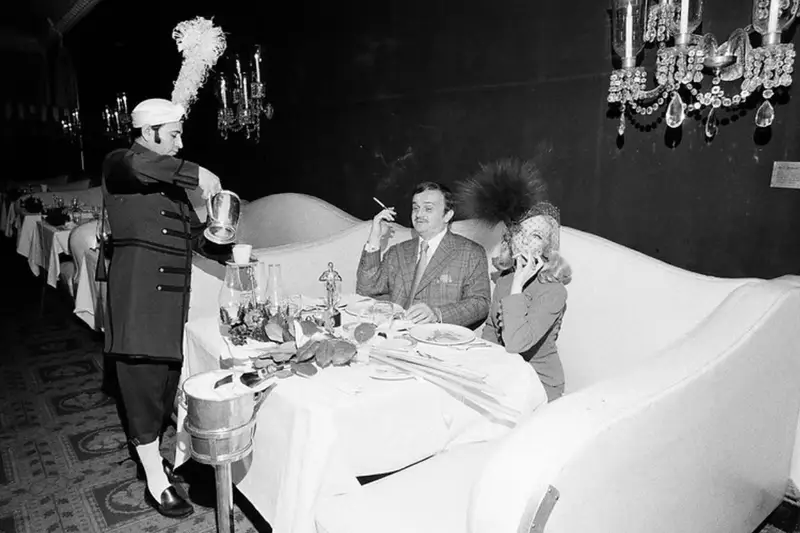 A vintage black-and-white photograph of diners sitting at Booth One inside the historic Pump Room restaurant in Chicago.