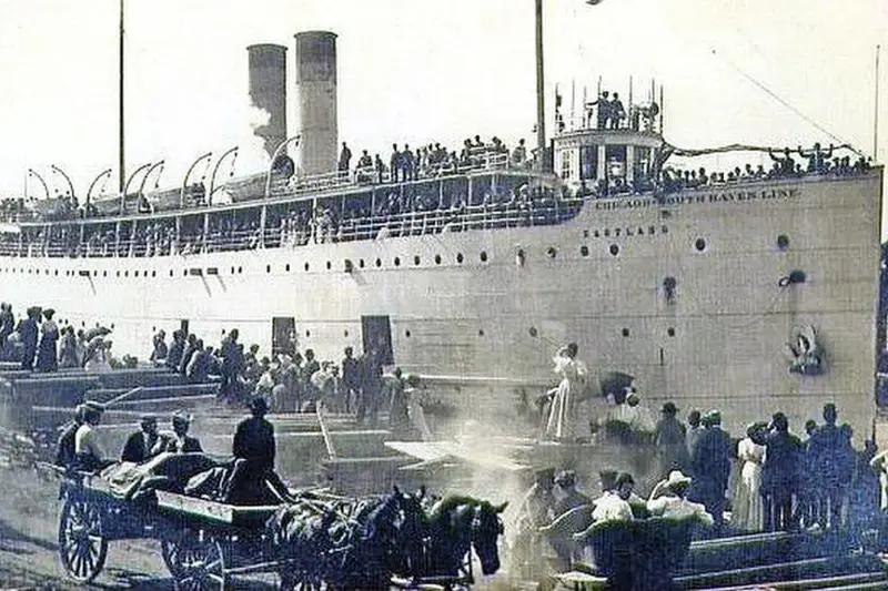 Vintage photograph of crowds boarding the white SS Eastland steamship at a Chicago dock, featuring horse-drawn wagons in the foreground and passengers lining the upper decks.