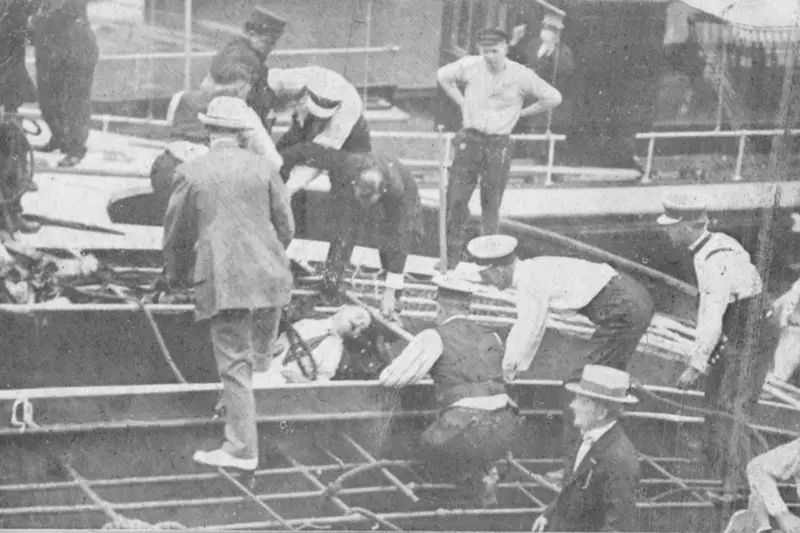 Archival black-and-white photograph showing police officers and civilian rescue workers standing on the exposed metal grid of the capsized SS Eastland, pulling a victim from the flooded wreckage.