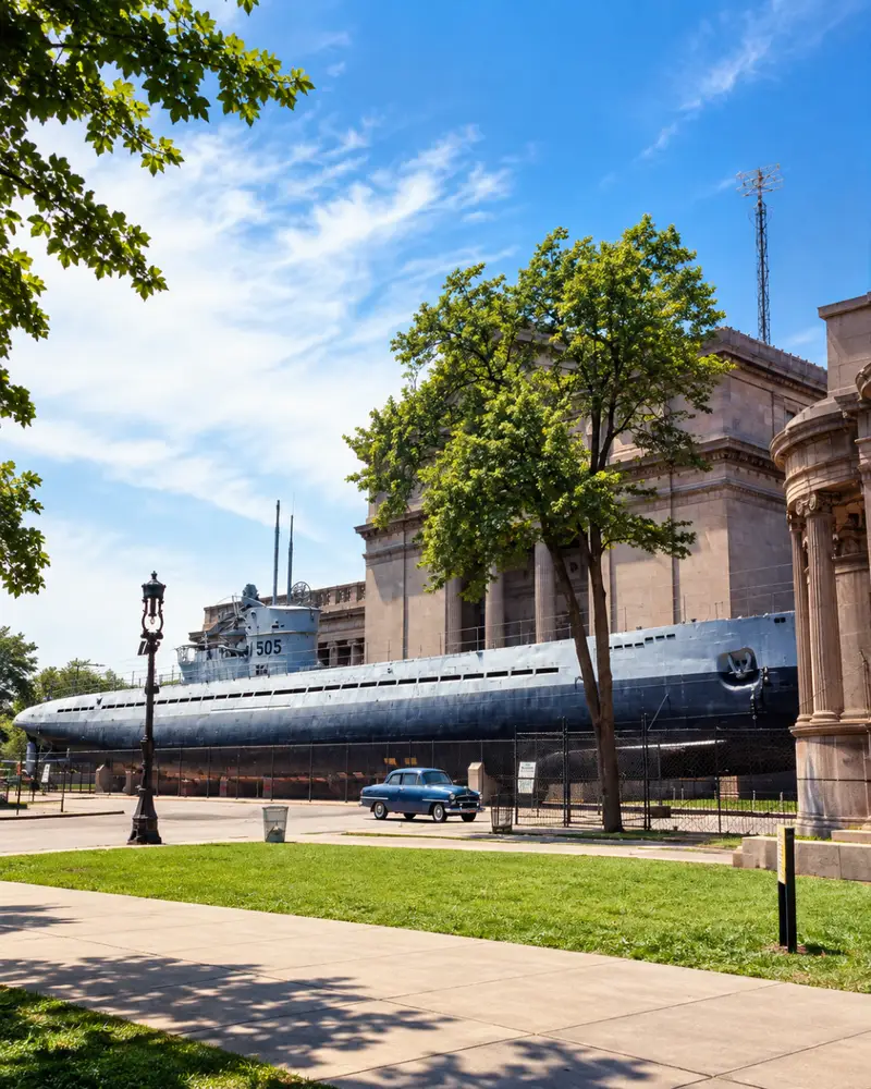 A vintage photograph of the captured WWII U-505 German submarine displayed outdoors next to the Museum of Science and Industry in Chicago, with classic 1950s cars parked nearby.